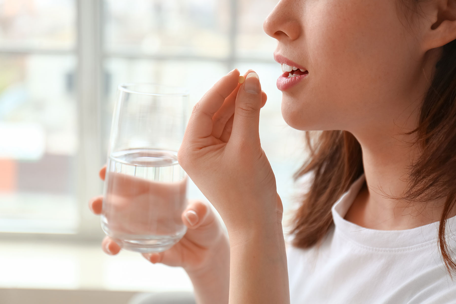 woman takes pills with water as part of medication-assisted recovery
