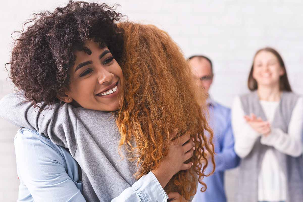 two women hug in group therapy