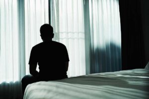 man sits on edge of bed and considers cocaine addiction treatment