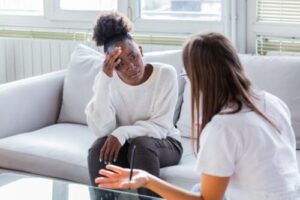 person sitting on couch talks to therapist about medication-assisted treatment